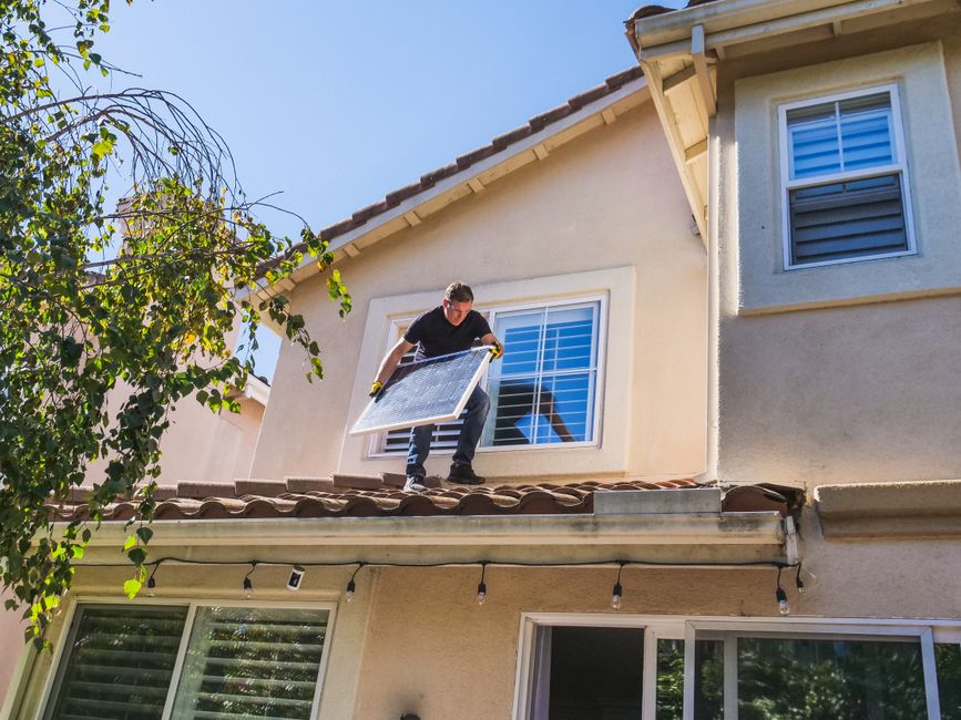 A worker on a house roof during exterior work.