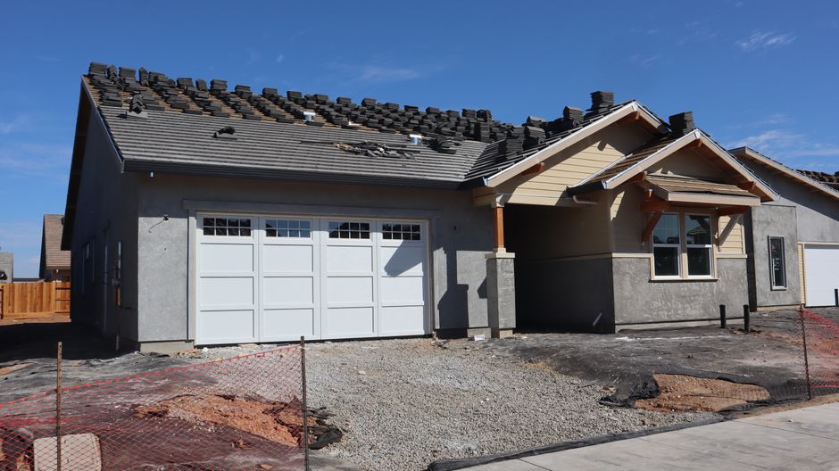 A suburban house under construction with roof work in progress.