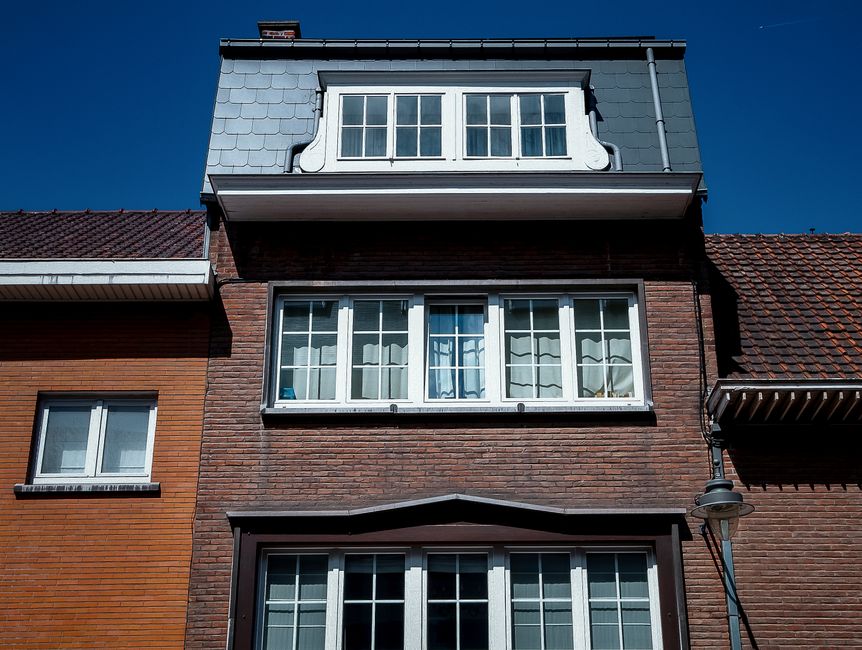 Close-up of a brick house facade with dormer windows.